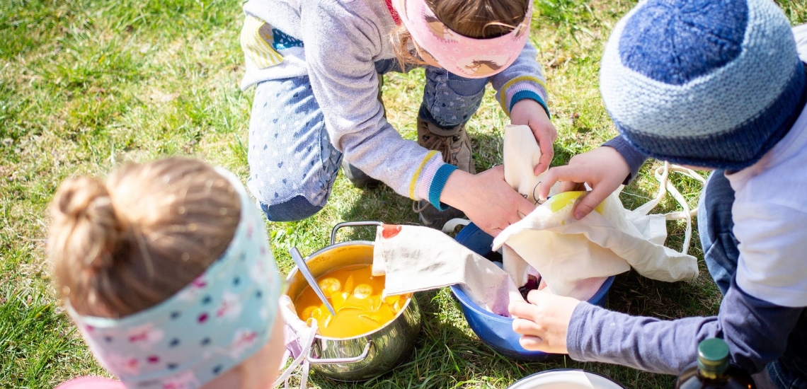 Kinder färben Eier auf Wiese 