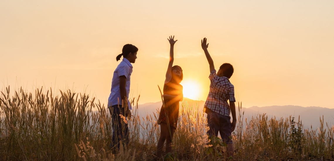 Kinder spielen auf einer Wiese im Sonnenuntergang 