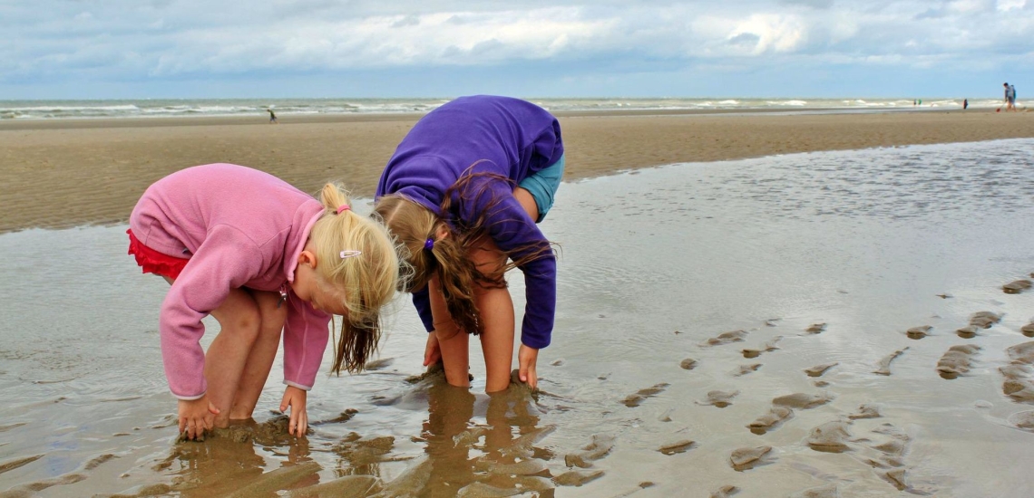 Zwei Kinder spielen am Strand im Sand