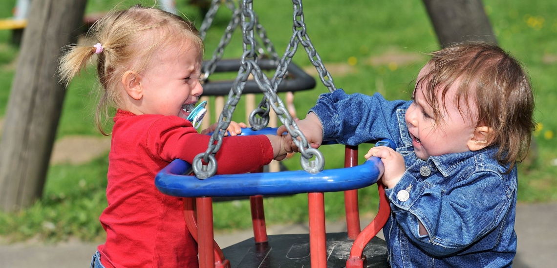 Kinder streiten auf Spielplatz und eine Schaukel und weinen 