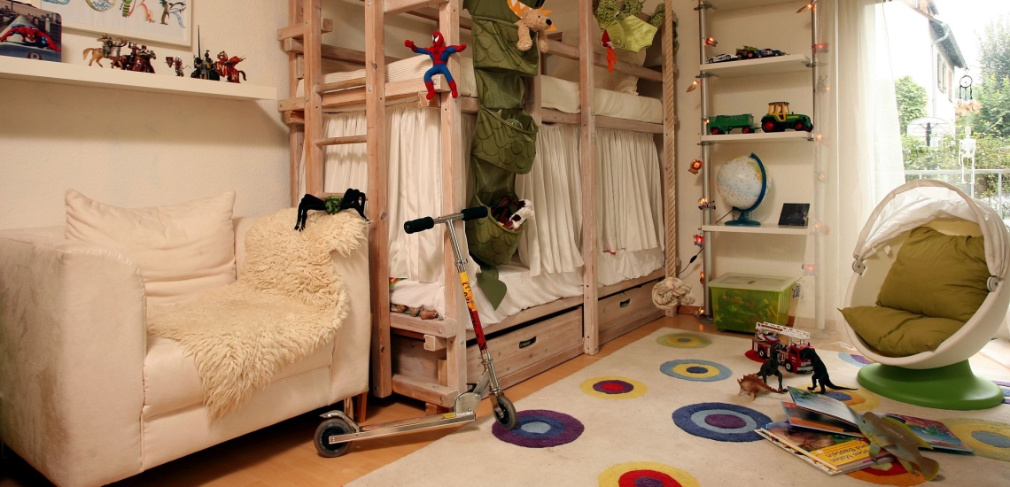 Kinderzimmer mit Bett, Sesseln, Spielsachen und Roller 