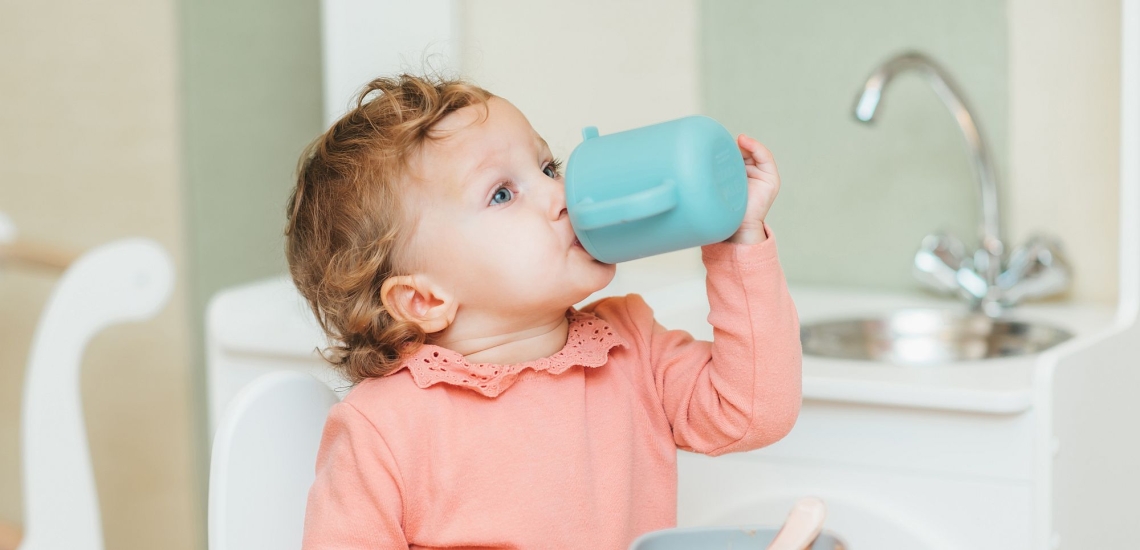Kleinkind trinkt aus Plastikbecher 