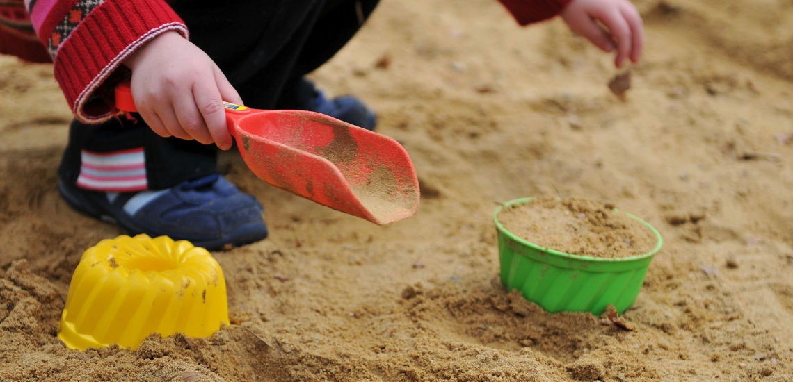 Kind spielt im Sandkasten mit Spielzeug 
