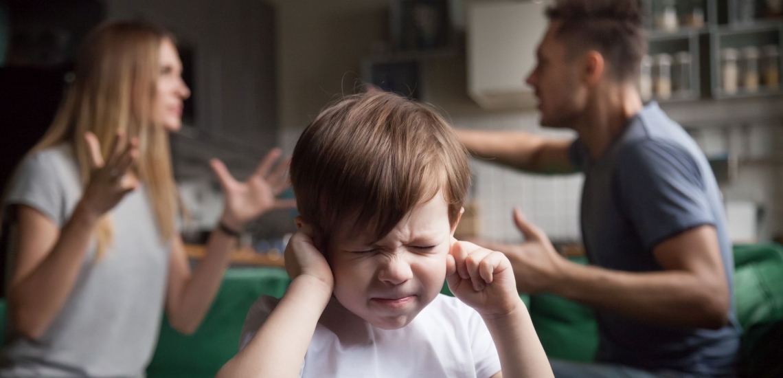 Eltern streiten und Kind hält sich die Ohren zu 