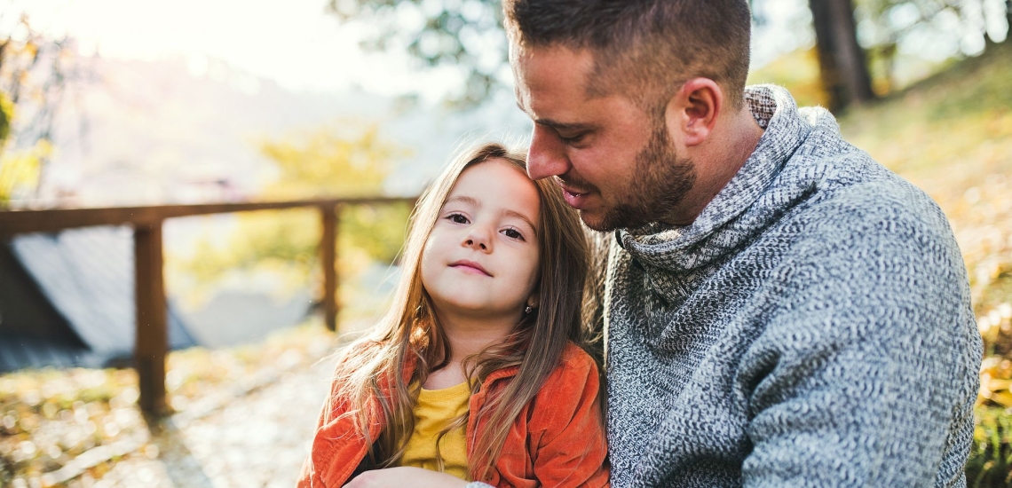 Vater und Tochter sitzen im Gespräch in der herbstlichen Natur 