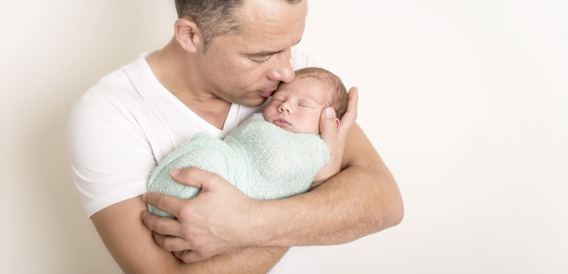 Vater hält schlafenden Säugling liebevoll im Arm