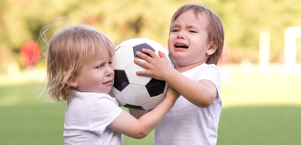 Zwei Kinder streiten sich um einen Ball 