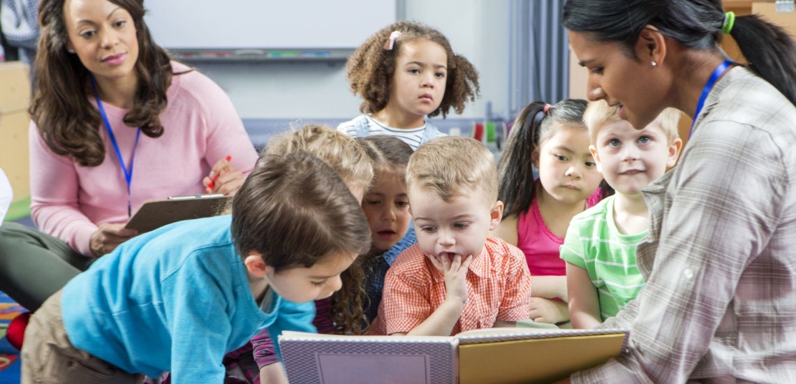 Kindergartenkinder lesen Buch mit Erzieherinnen 