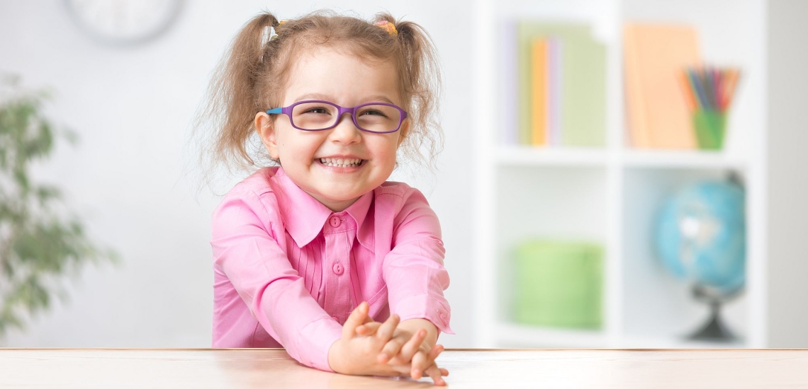 Mädchen mit Brille fröhlich und verschmitzt in Kita 