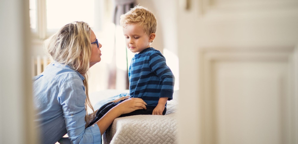 Mutter spricht mit kleinem besorgt wirkenden Sohn 