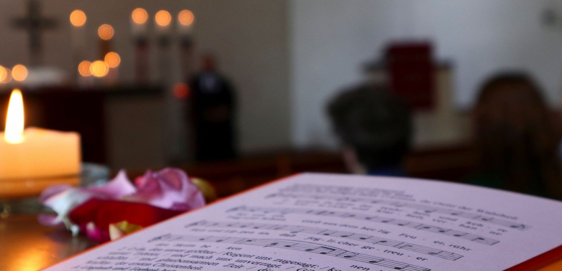 Liedblatt und Kerze auf Kirchenbank 