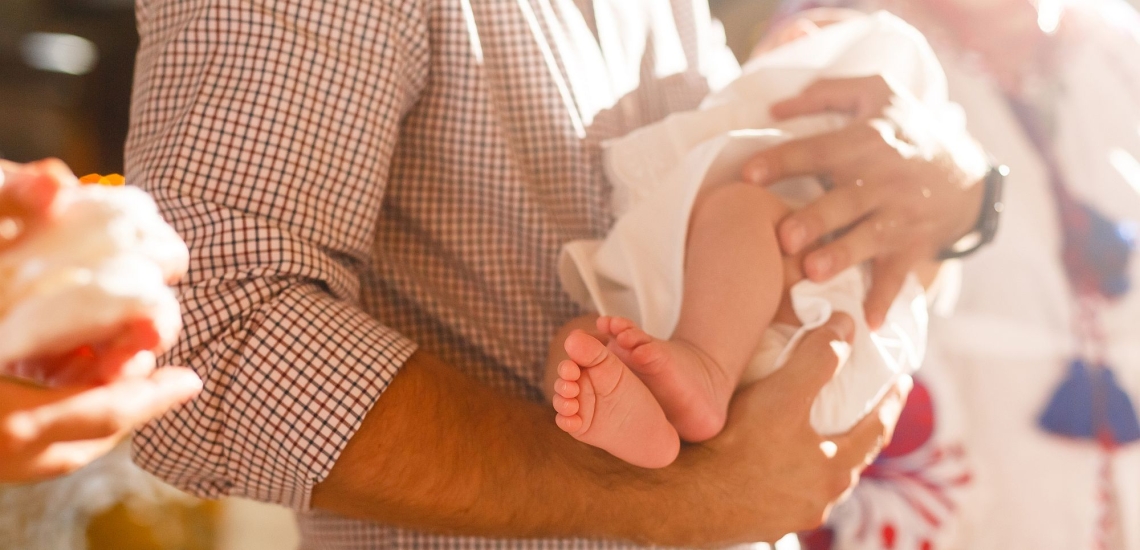 Mann in Kirche hält Baby im Arm 