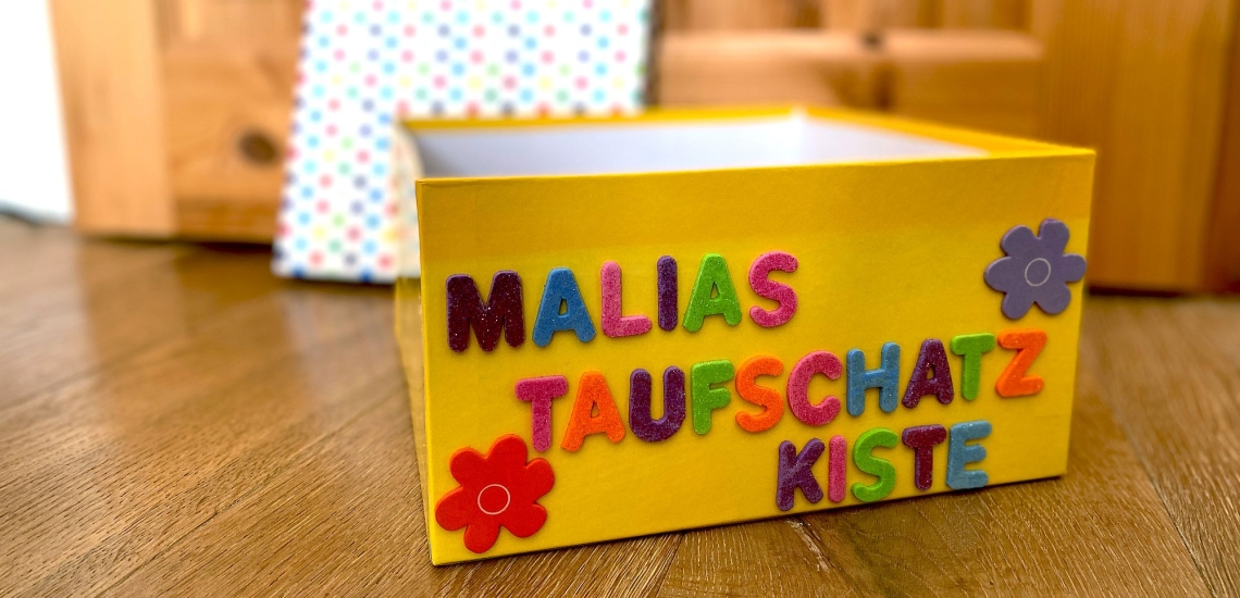 mit bunten Buchstaben und Blumen beklebter Karton als Erinnerung an die Taufe 