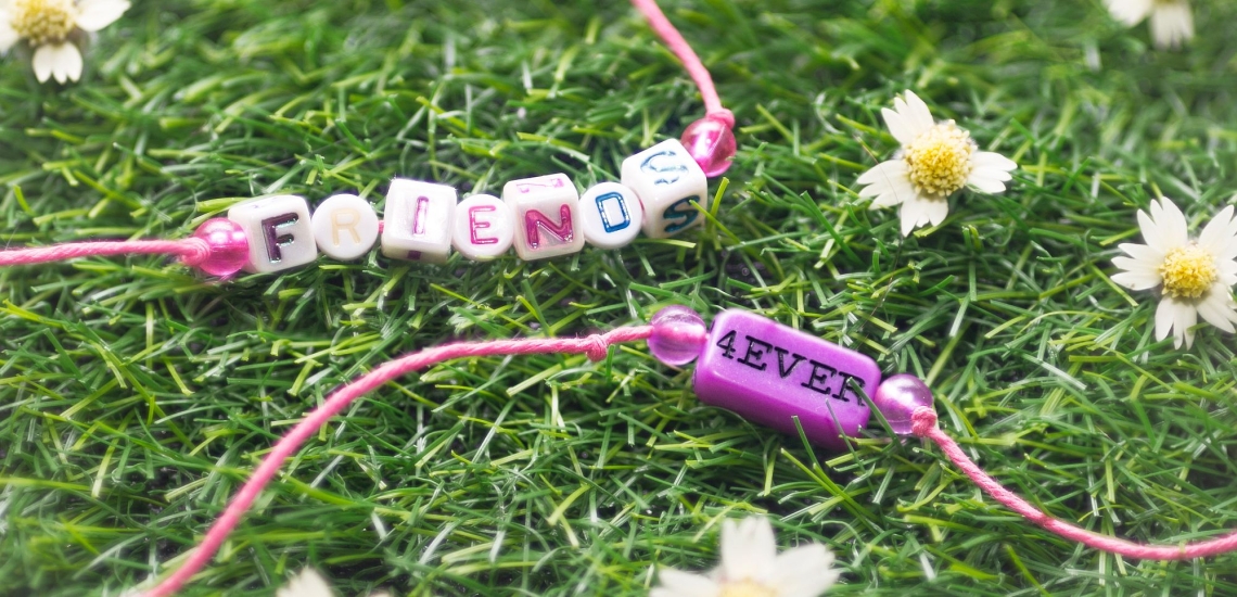 zwei Perlenarmbänder mit Schrift friends forever auf einer Blumenwiese