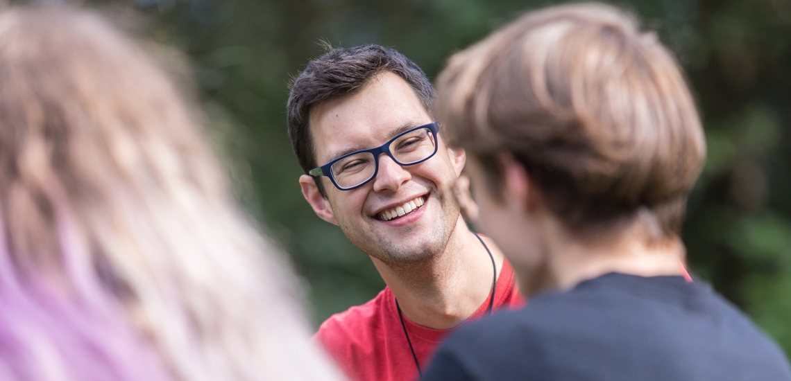 Ein junger Salesianer Don Boscos unterhält sich ausgelassen mit zwei Jugendlichen.