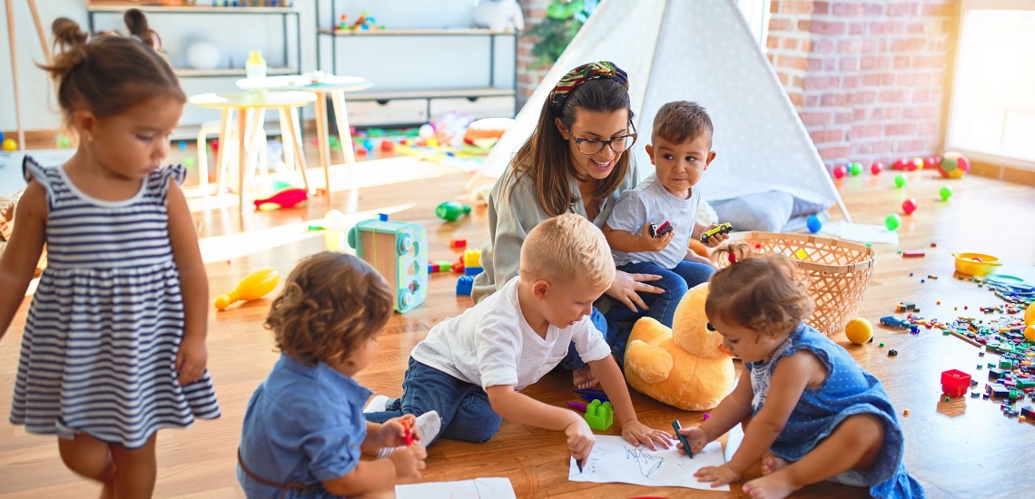 Erzieherin mit Kindern in Kinderkrippe 