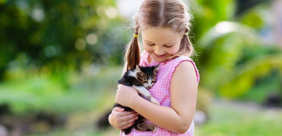 Mädchen hält Katzenbaby im Arm