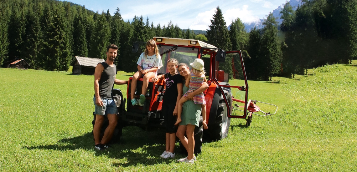 Die gesamte Pflegefamilie steht auf dem Feld vor dem Traktor.