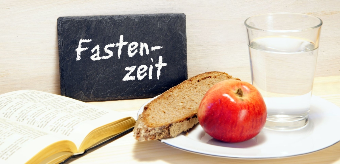 Brot, Apfel, Bibel, Wasser und Schild mit Aufschrift Fastenzeit