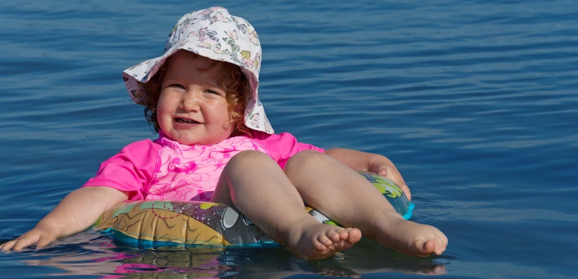 Ein Kleinkind lässt sich entspannt im Schwimmring treiben.