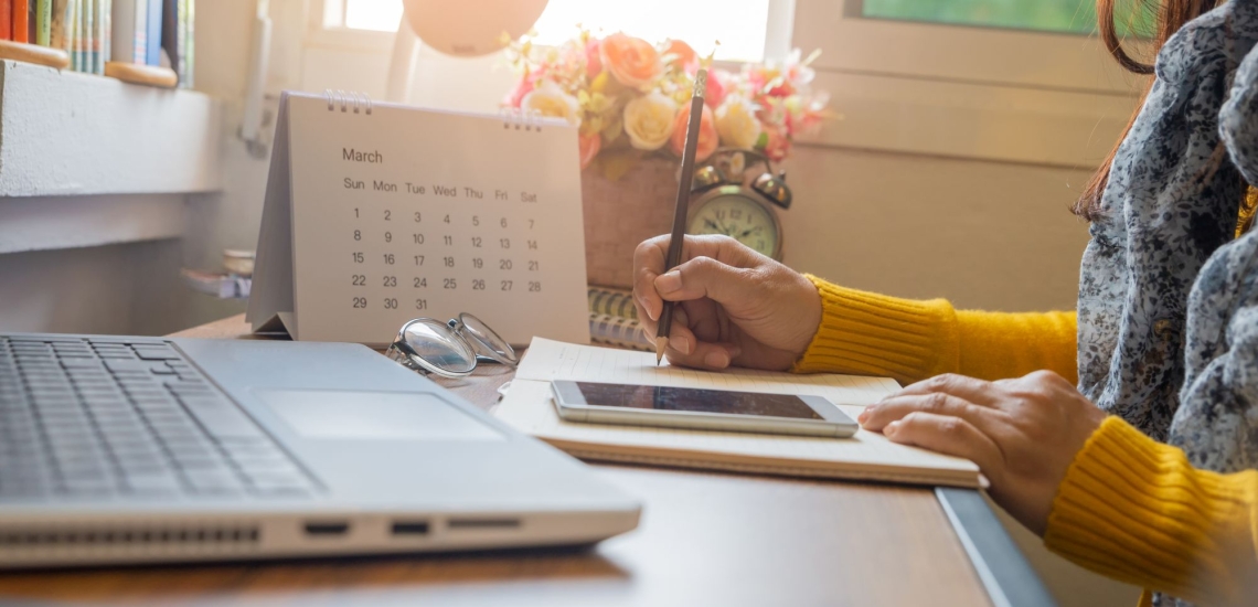 Hände von Frau mit Notebook, Handy und Tischkalender 