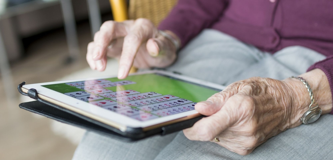Hände von alter Frau mit Spiel auf Tablet 