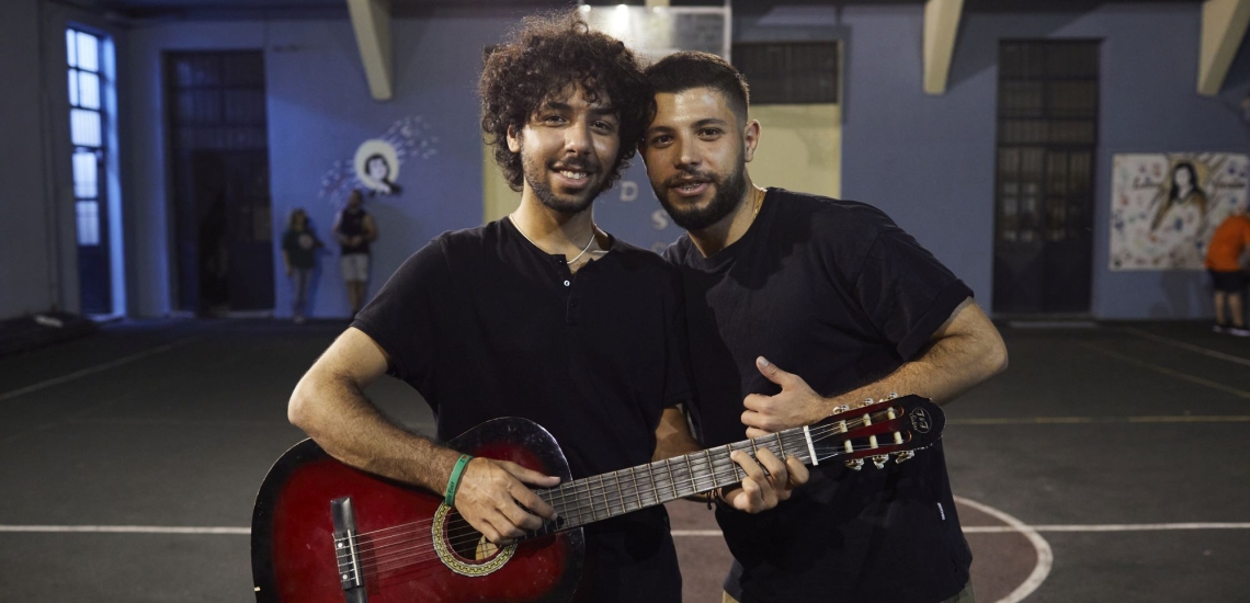 Zwei junge Männer, einer davon hält eine Gitarre in der Hand
