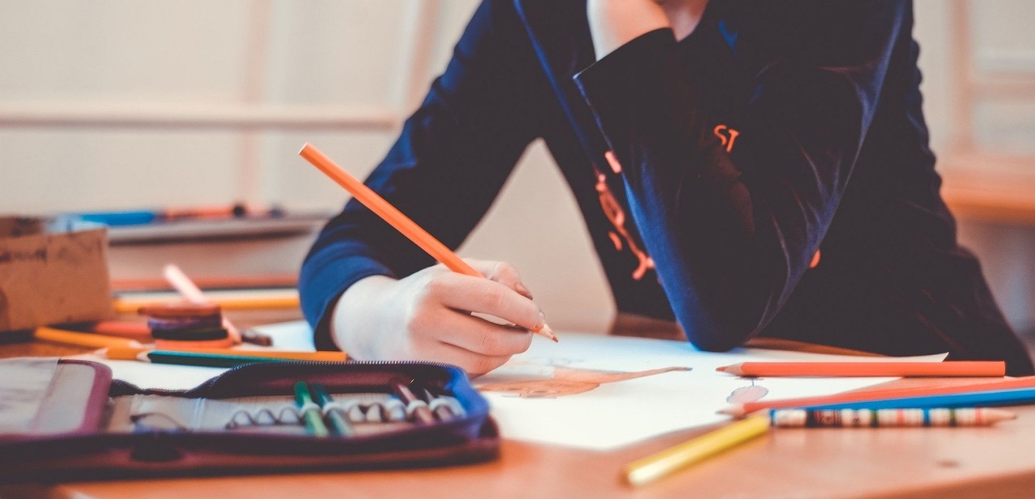 Hand von Schüler mit Stift und Heften 