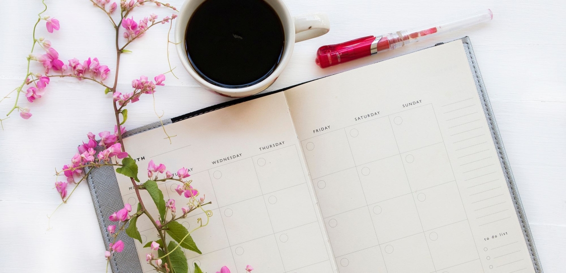 Kalender mit Kaffetasse, Blumen und Stift 