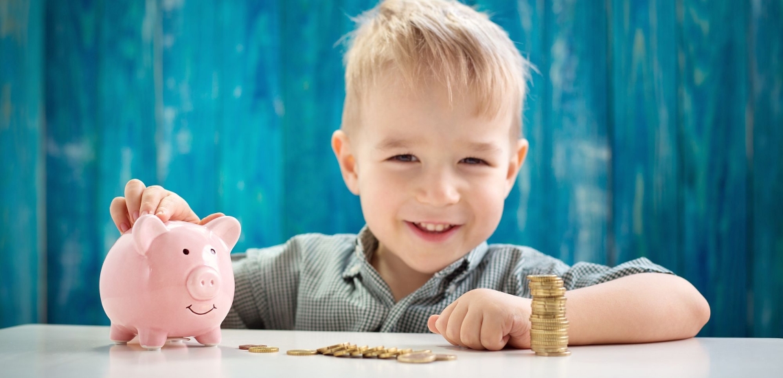 Junge lachend mit Sparschwein und Münzen 