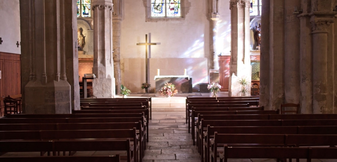 Leere Kirche in die das Sonnenlicht durch die bunten Fenster fällt