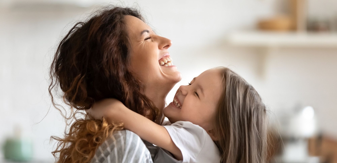 Mutter und Tochter umarmen sich und lachen 
