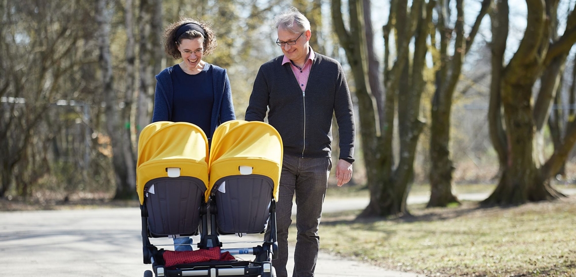 Eltern schieben Zwillingskinderwagen im Park 
