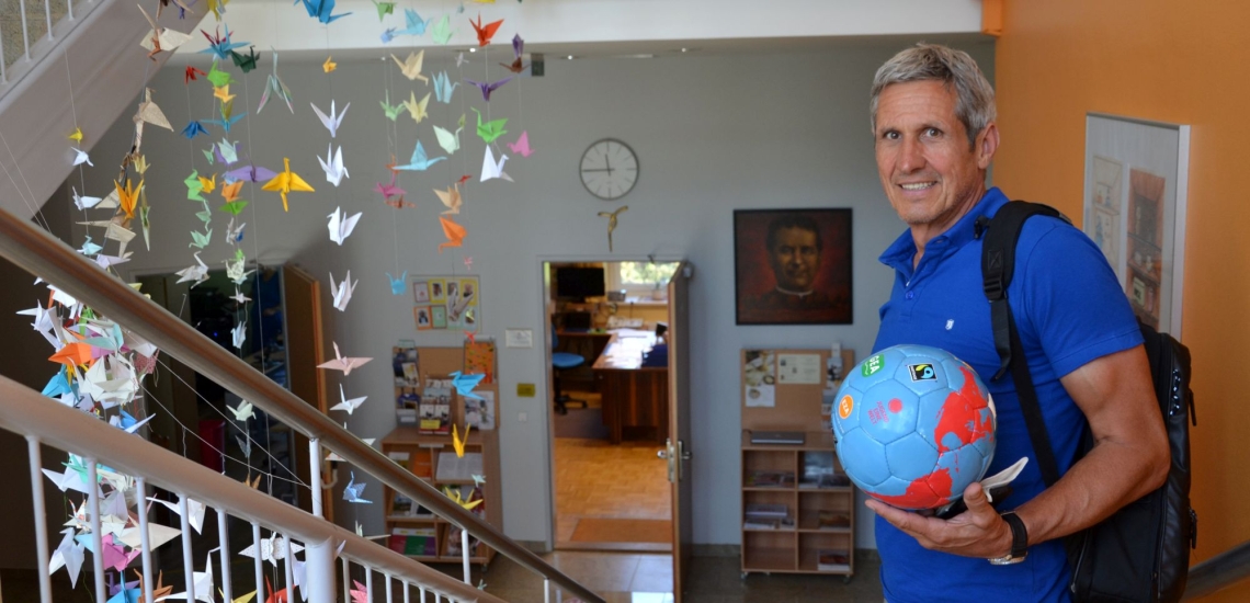 Lehrer mit Globus im Treppenhaus der Schule
