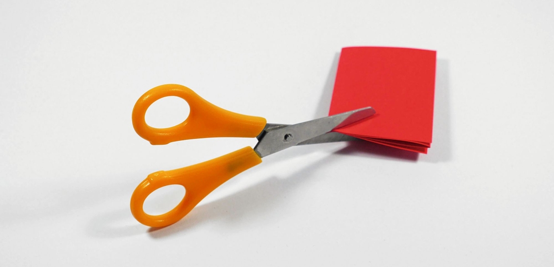 Schere schneidet in rotes zusammengefaltetes Papier