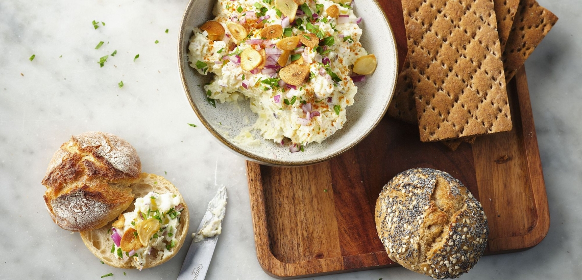 Kartoffelkäse in Schale mit Brot, Semmeln und Messer auf einem Brett