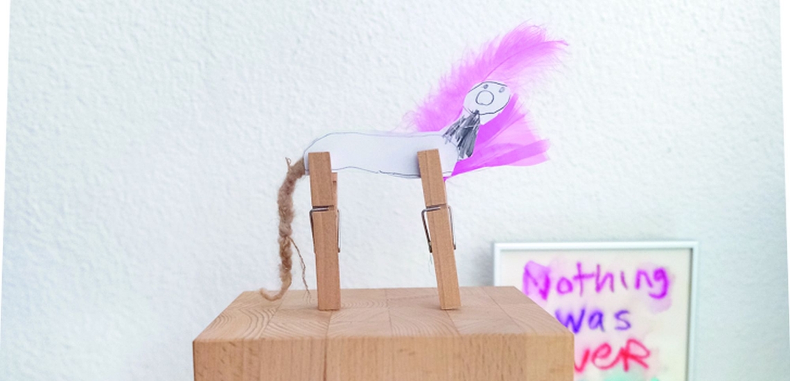 Kinderkunstwerk aus Klammern, Papier und Federn auf einem Holzsockel 