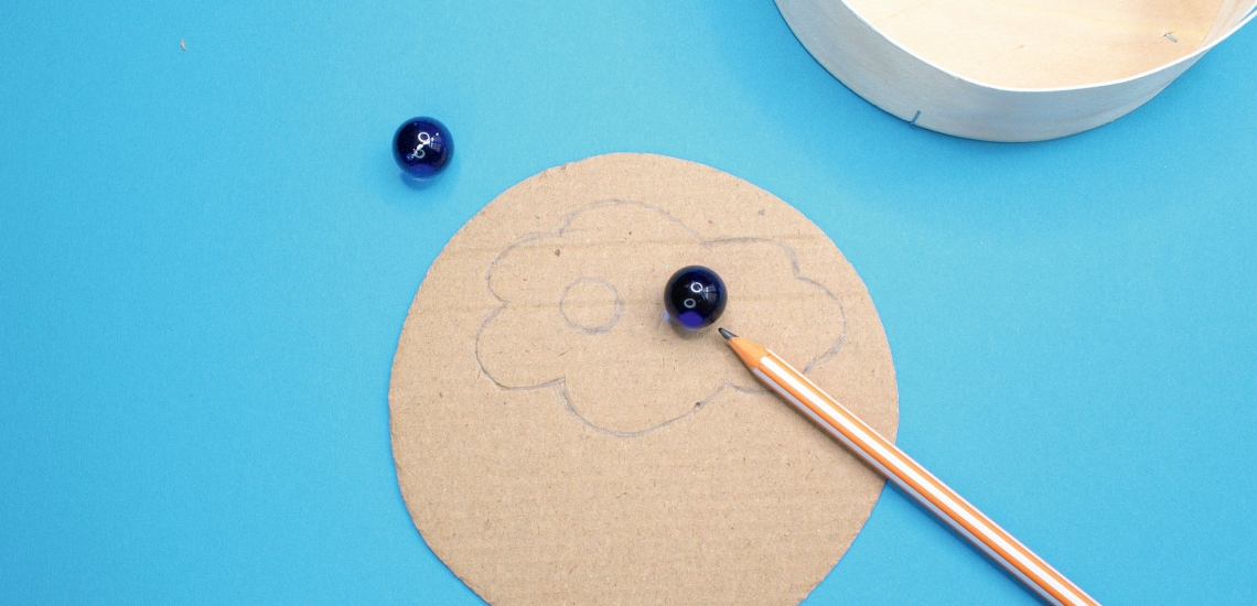 bemalter Boden von Pappschachtel mit Stift und Murmeln 