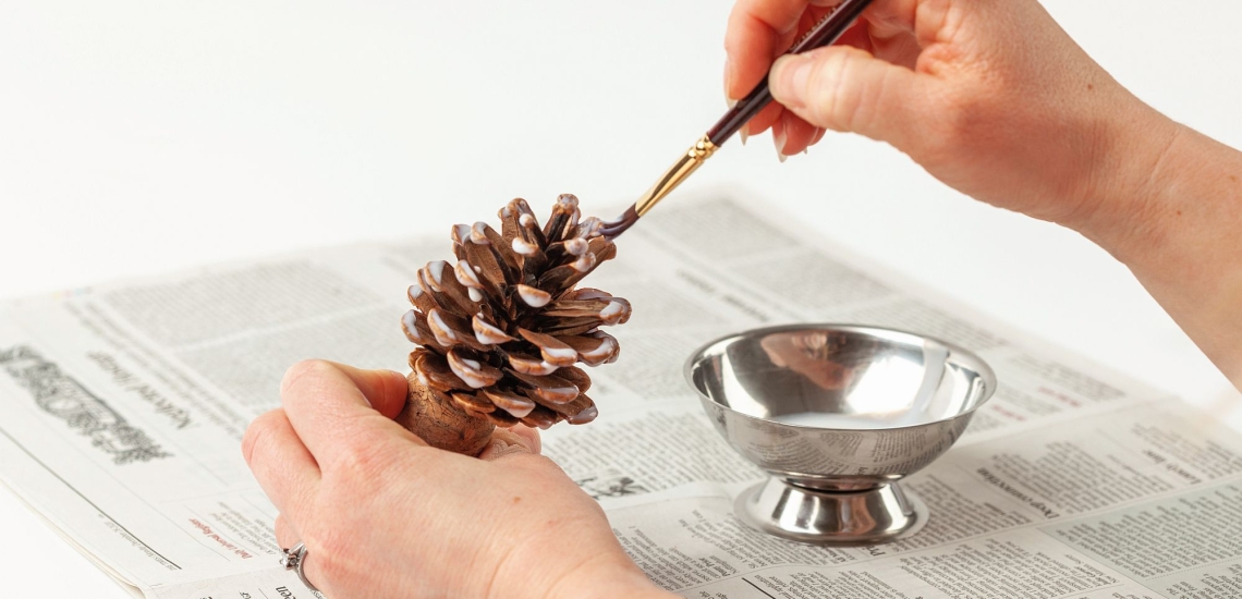 Pinienzapfen wird mit Kleister bestrichen