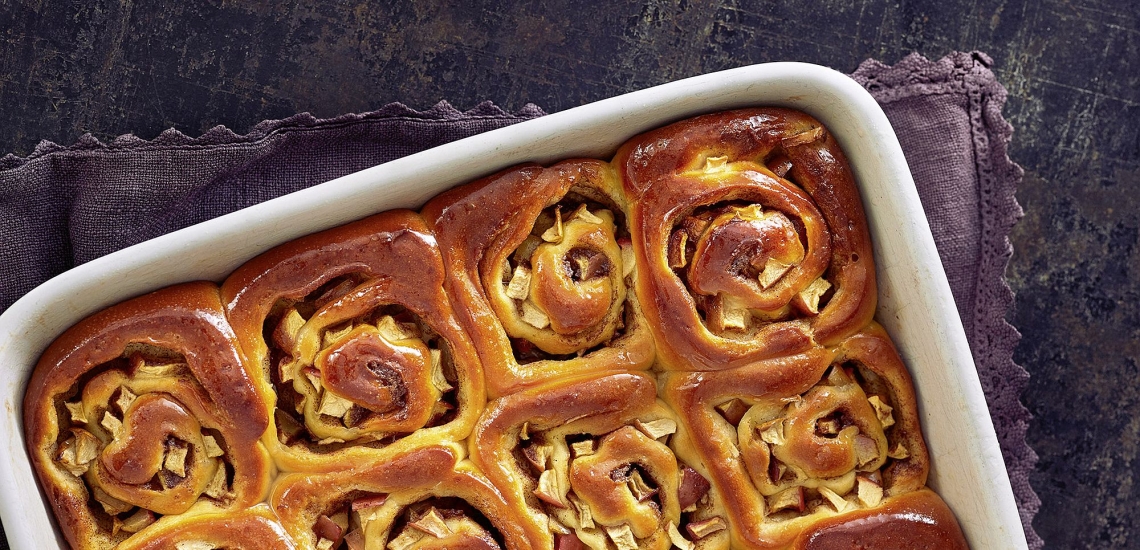 Frisch gebackene Schnecken in Auflaufform auf Holztisch 