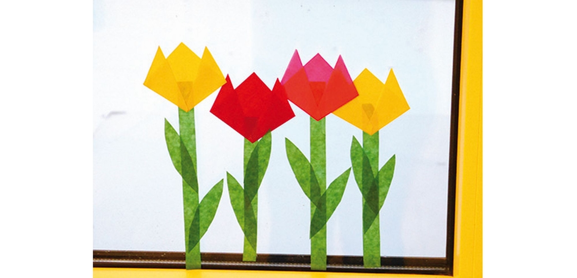 Vier selbst gemachte Tulpen aus Transparentpapier am Fenster
