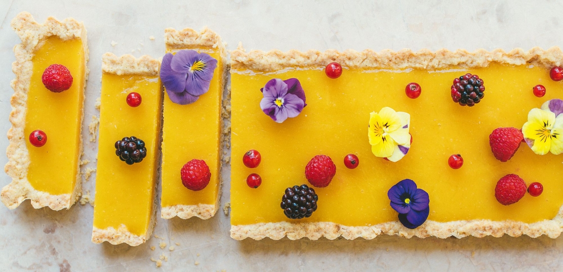 Zitronenschnitten mit frischen Beeren und Blüten 