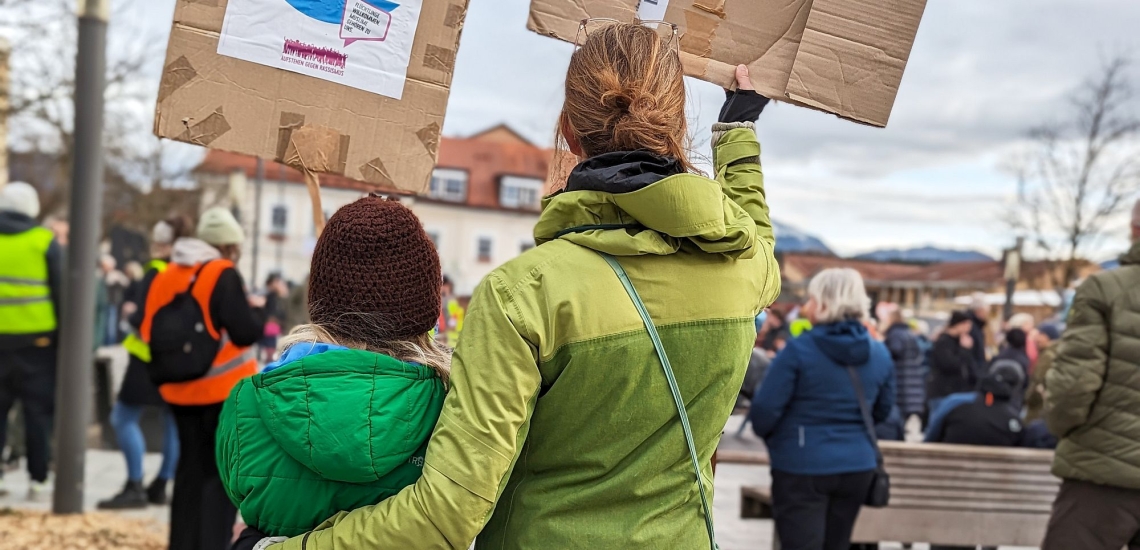 Mutter und Kind halten bei einer Demonstration Plakate hoch