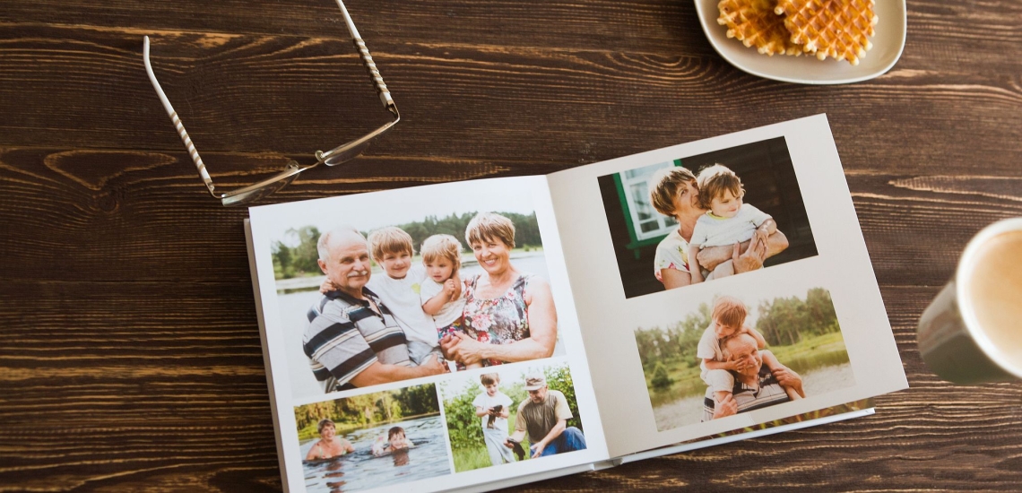 Fotoalbum mit Familienfotos auf Tisch mit Brille, Keksen und Kaffeetasse 