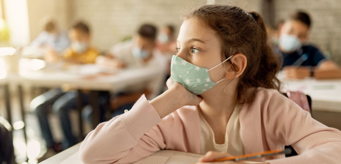 Mädchen in Klassenzimmer schaut traurig aus dem Fenster 