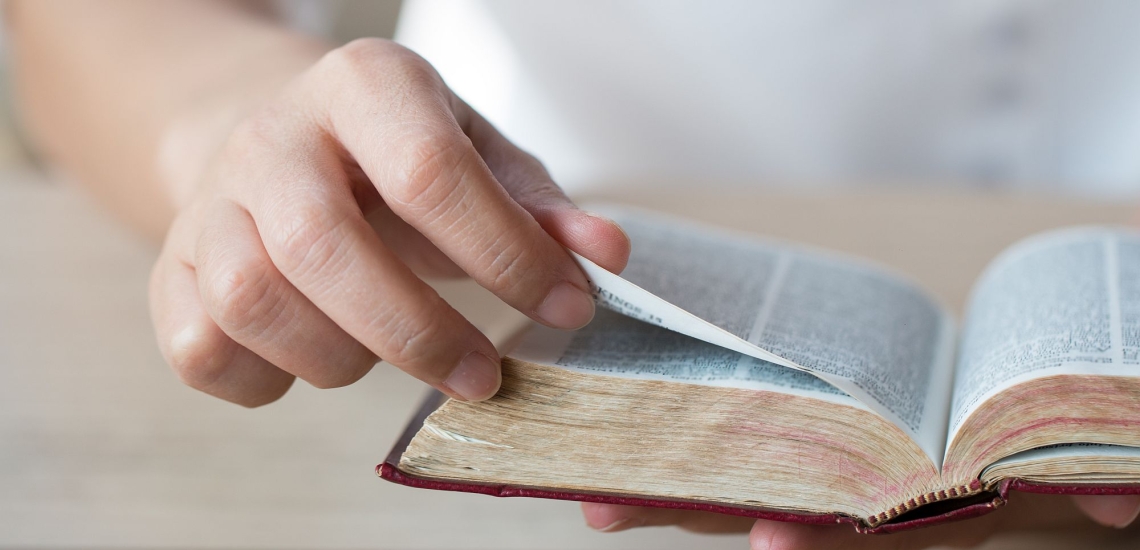 Hand blättert in Bibel beim Vorlesen in der Familie 