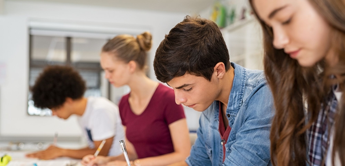 Schülerinnen und Schüler in Klassenzimmer schreiben Prüfung