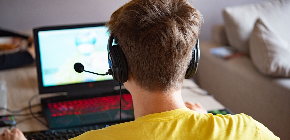 Jugendlicher am PC mit Headset bei Online-Spiel 