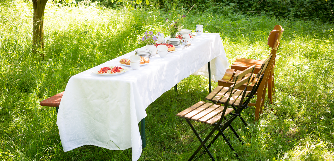 Gedeckter Tisch mit Stühlen auf einer Wiese