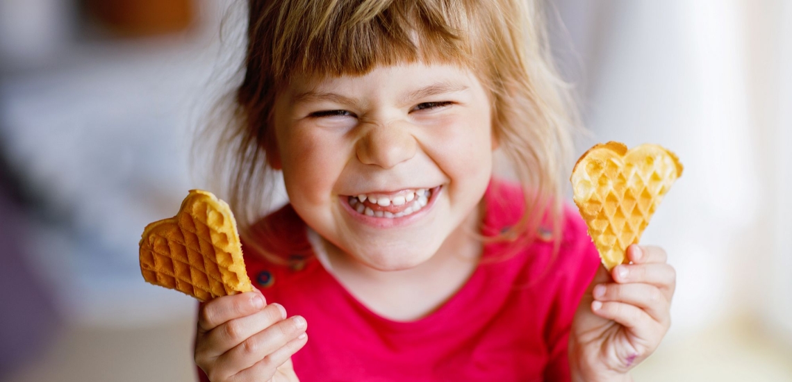 Kind hält fröhlich zwei Waffelherzen in den Händen